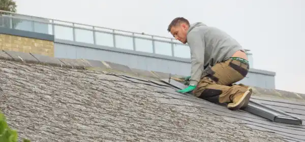 UK roofer on pitched roof repairing storm damaged tiles