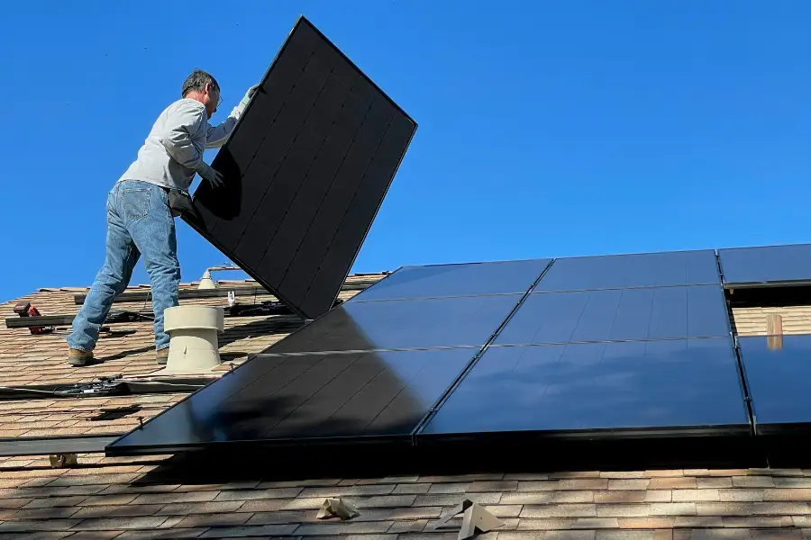 Solar panel installer fitting photovoltaic panels on UK residential roof