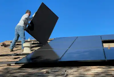 Solar panel installer fitting photovoltaic panels on UK roof
